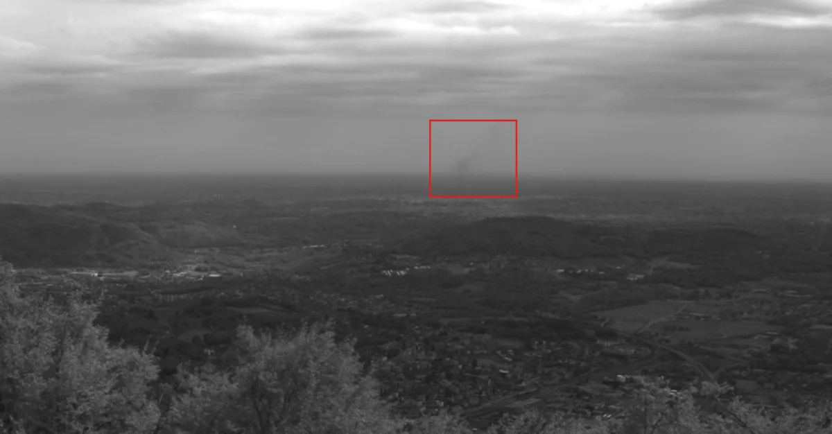 Graustufenbild der HUVI.NOMAD Kamera über der Ebene bei Mailand, rot markiert die erkannte Rauchsäule in rund 17 km Entfernung